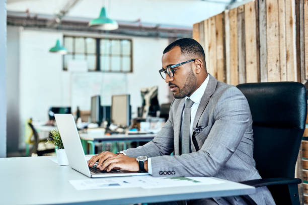 Shot of a young businessman working on a laptop in an office
